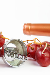 FIRST PLANE OF GRAPES WITH WINE BOTTLE AND CORKSCREW ON WOODEN TABLE. VINTAGE TIME