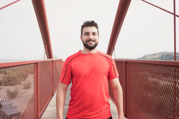 Sports mid adult man warming on a bridge after running