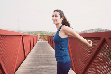 mid adult woman warming up on a bridge before and after run
