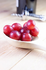 GRAPES ON WOODEN SPOON WITH WINE BOTTLE AND CORKSCREW ON WOODEN TABLE. VINTAGE TIME
