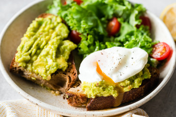 Healthy toast or sandwich with avocado and poached egg, closeup view