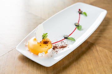 Yellow mousse-cake. French dessert, blueberry, mint and a piece of meringue on a white plate. Stylishly decorated. Restaurant menu