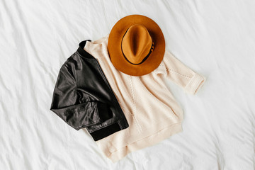 Leather jacket and white warm sweater with brown hat on white sheet. Women's stylish autumn or...
