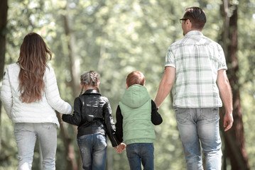 rear view. family with two children walking hand in hand in the Park.