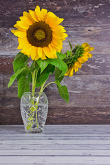 sunflowers in a glass flower vase against wooden background