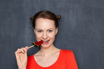 Fototapeta premium Portrait of cute happy girl biting lollipop and smiling broadly