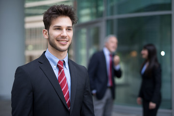 Smiling young businessman walking in a business environment