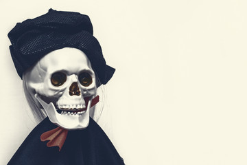 Creepy smiling skeleton skull wearing carnival costume for halloween close up on white background with copy space, death and mystery concept, halloween