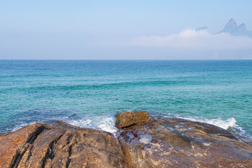 Seascape of Rio de Janeiro beaches depicting Arpoador beach and rocks with a calm green sea