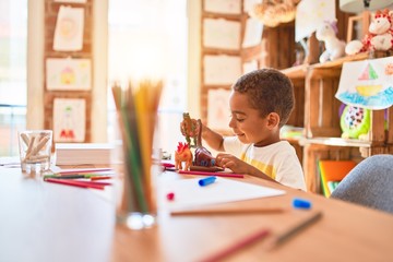 Beautiful african american toddler playing with dinosaurs toy on desk at kindergarten