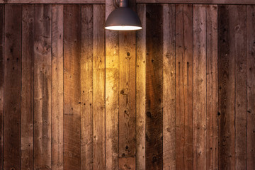 Glowing light bulb on wooden background. Light falling from old vintage lamp on wall.