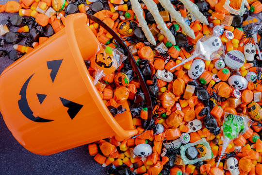 Halloween candy spilling out of orange pumpkin bucket