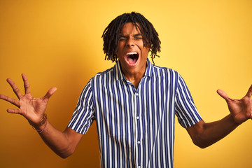 Afro man with dreadlocks wearing casual striped t-shirt over isolated yellow background celebrating...