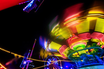 Abstract colorful funfair carosuell in neon colors in motion at a fun fair