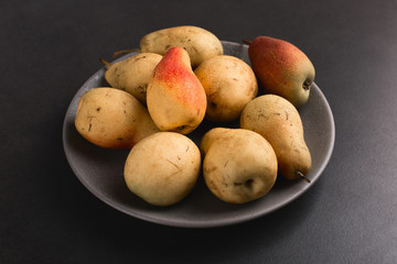 Fresh juicy appetizing pears on a gray plate, summer concept, copy space.