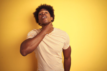 American man with afro hair wearing striped t-shirt standing over isolated yellow background Touching painful neck, sore throat for flu, clod and infection