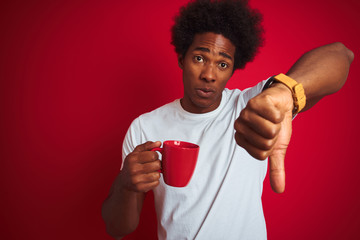 Young african american man drinking a cup of coffee standing over isolated red background with...