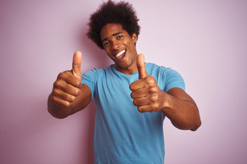African american man with afro hair wearing blue t-shirt standing over isolated pink background...