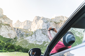 Man Laid Down on the Car Bonnet Taking Picture to the Mountain.