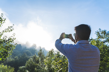 Fototapeta premium Indian Man Taking a Picture to the Sun Rising From the Mountain.