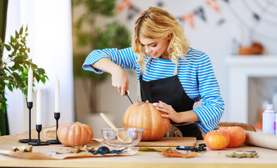 happy girl is cutting  pumpkin and is preparing for holiday Halloween.