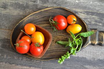 Fototapeta na wymiar Delicious cherry tomatoes on a wooden plate, top view