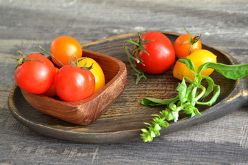 Rustic plate with fresh ripe tomatoes on wooden table, green basil. Russian cuisine