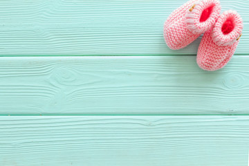 Pink knitted footwear for kids on mint green wooden background top view space for text