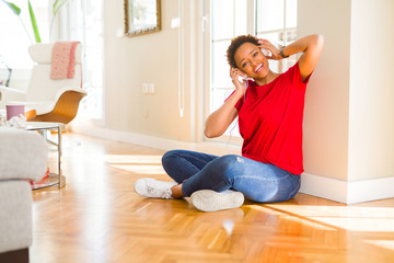 Beautiful young african american woman with afro hair listening to music and dancing wearing headphones