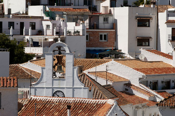 Bell of christian church located amidst tiled roofs of houses on sunny day on town street