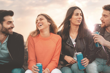 Young friends group drinking together canned beers outdoors at sunset