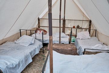 Reconstruction of a vintage hospital for the treatment of wounded in battle. Large tent with beds...
