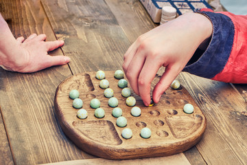 Two people play an ancient board game Mill. Reconstruction of entertainment and leisure in the old days. Vintage intellectual game for two players.