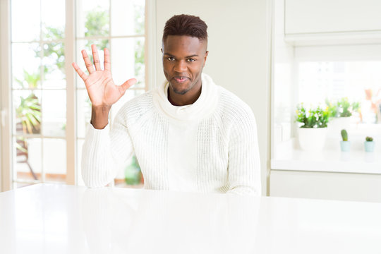 Handsome african american man on white table showing and pointing up with fingers number five while smiling confident and happy.