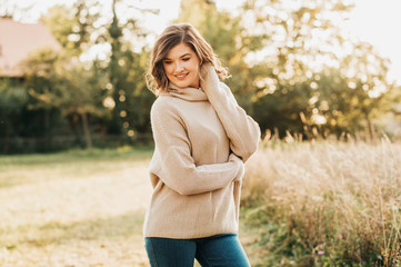 Outdoor portrait of beautiful young woman in the park, wearing warm knitted pullover