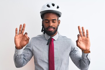 African american businessman with braids wearing bike helmet over isolated white background relax and smiling with eyes closed doing meditation gesture with fingers. Yoga concept.