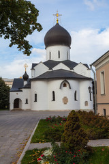 Fototapeta na wymiar White-stone church in the Martha-Mariinsky monastery of mercy. In the foreground are flower beds with small trees