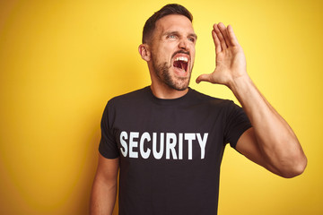 Young safeguard man wearing security uniform over yellow isolated background shouting and screaming...