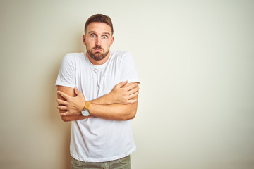 Young handsome man wearing casual white t-shirt over isolated background shaking and freezing for...