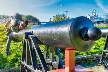 Crazy man tourist have fun with the vintage canon that located in the garden of Bergenhus Fortress, Bergen, Norway - 291385619