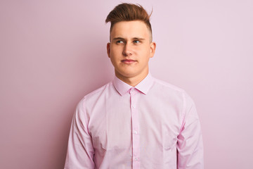 Young handsome businessman wearing elegant shirt standing over isolated pink background smiling looking to the side and staring away thinking.