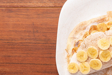Tapioca filled with banana, cinnamon and condensed milk, on wooden background. Flatbread made from cassava (also known as casabe, bammy, beiju, bob, biju).