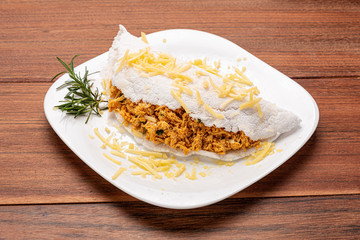 Tapioca filled with chiken breast and cheese on wooden background. Flatbread made from cassava (also known as casabe, bammy, beiju, bob, biju).