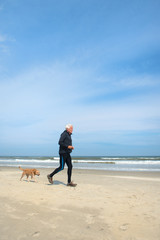 Senior man sporting with dog at beach