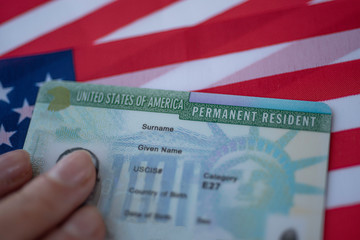 Permanent Resident Green card  of United states of America on flag of USA. Above close up view.