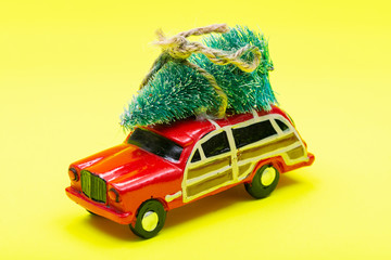 Christmas Tree on a toy car on bright yellow background. Winter Holidays celebration concept.