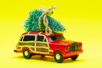 Christmas Tree on a toy car on bright yellow background. Winter Holidays celebration concept.