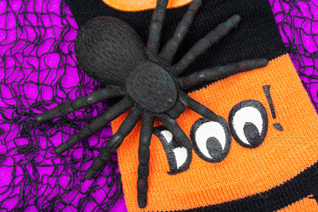 Black Spider and striped black and orange funny socks on bright purple background. Boo! Halloween Holiday celebration concept.