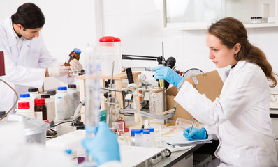 Female chemist writing results of experiments