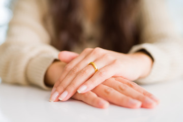 Close up of woman hands on each other wearing a golden alliance for marriage